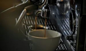 فنجان قهوه زیر دستگاه اسپرسو ساز در حال عصاره گیری قهوه