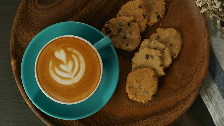 فنجان قهوه و شیرینی در کنارش