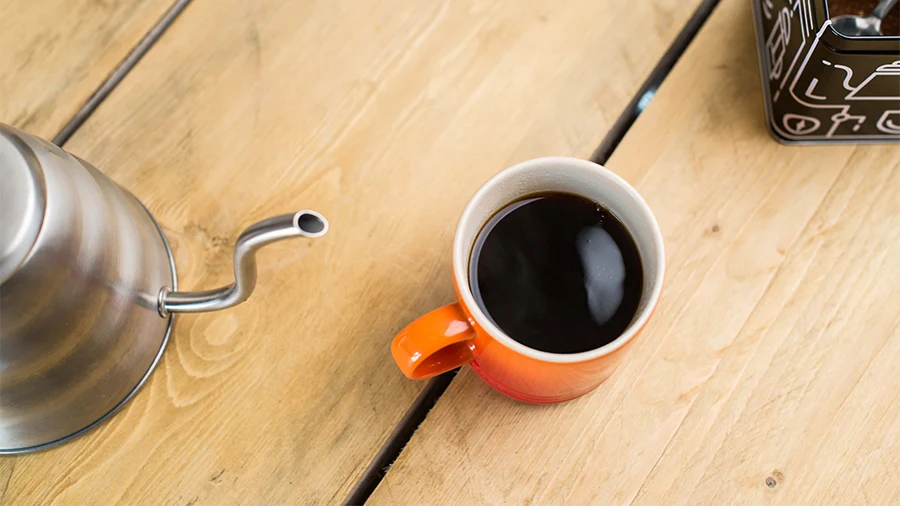 یک لیوان قهوه روی میز چوبی