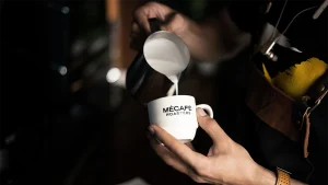 یک باریستا در حال ریختن شیر بخار داده شده در یک فنجان قهوه