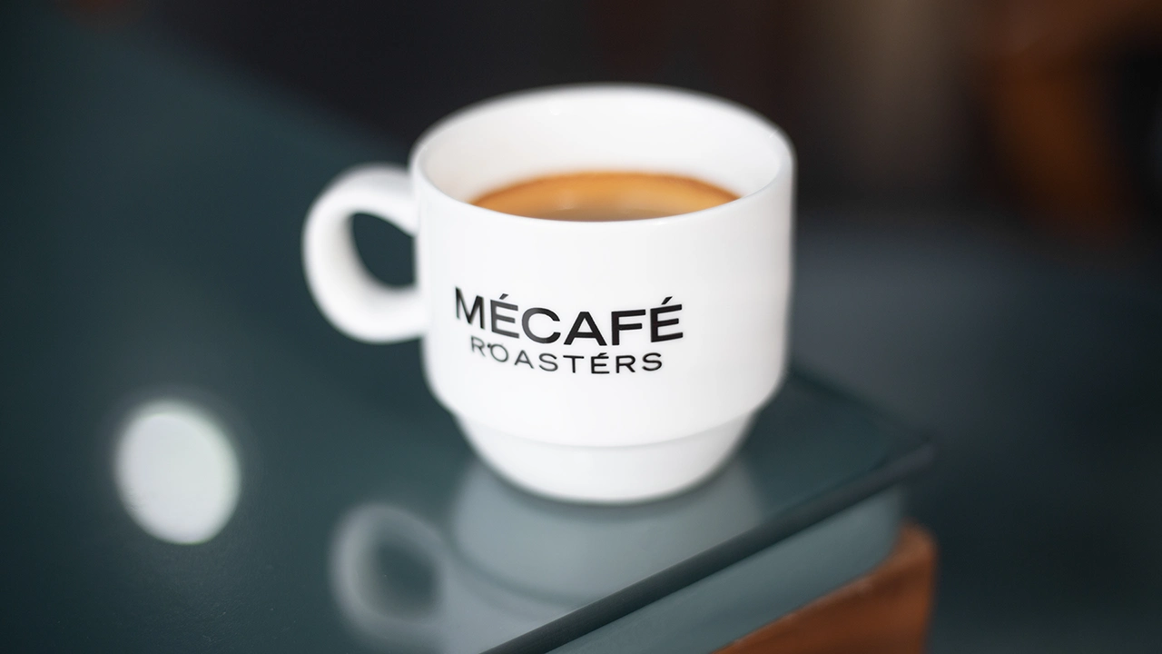mecafe roasters cup on the edge of a cafe table